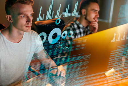 Two men working n their computers with data charts