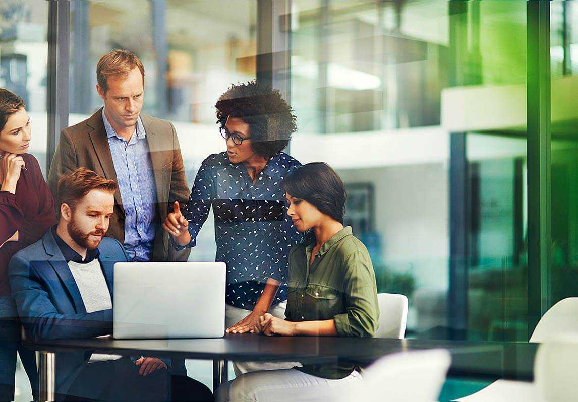 Young business professionals meeting around a laptop on a desk