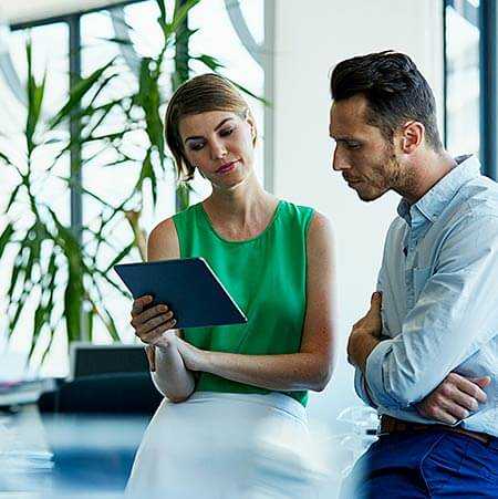 Two business professionals — a man and a woman — looking at a mobile device